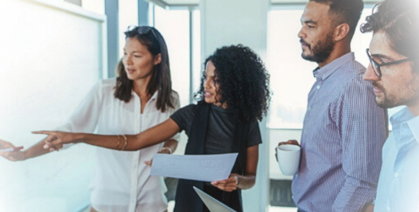 2 femmes et 2 hommes en brainstorming devant un tableau blanc